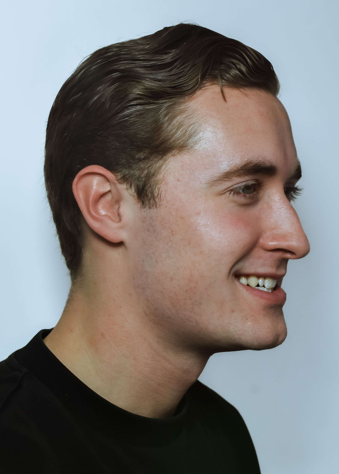 Side profile of a man with short brown hair against a light blue background, Earasers nearly invisible