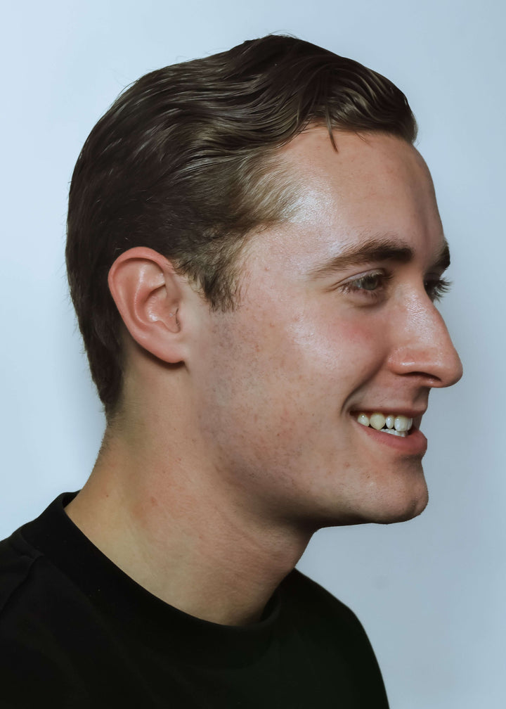 Side profile of a man with short brown hair against a light blue background, Earasers nearly invisible