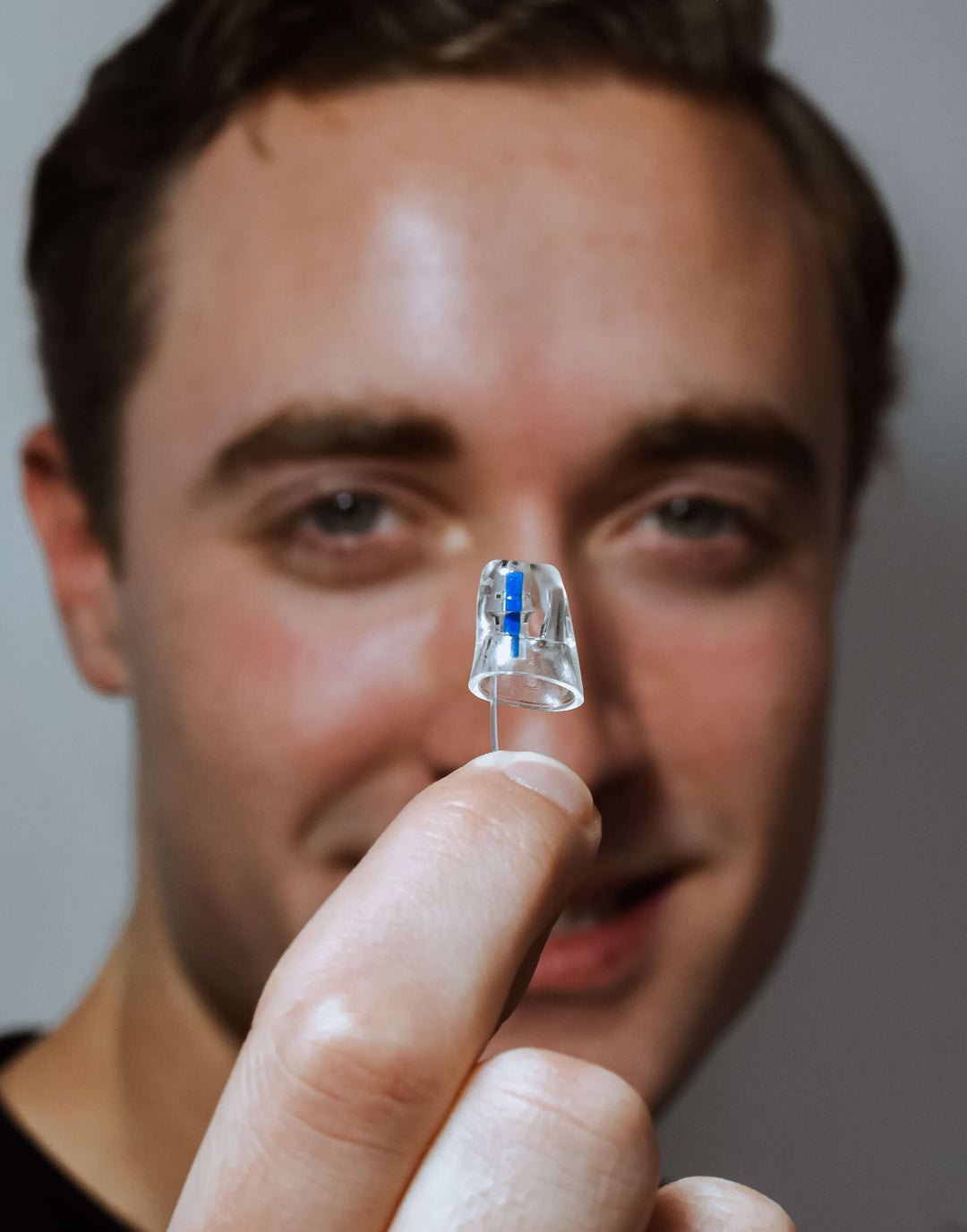 Person holding a small Earasers with blue indicator close to their face