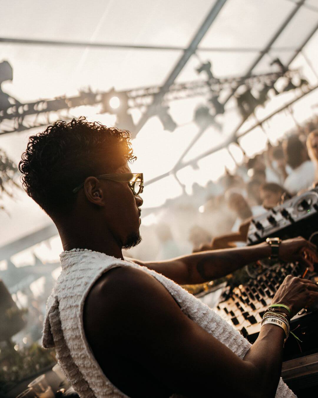 right side profile of a dj mixing music in front of a crowd with an earplug in his ear