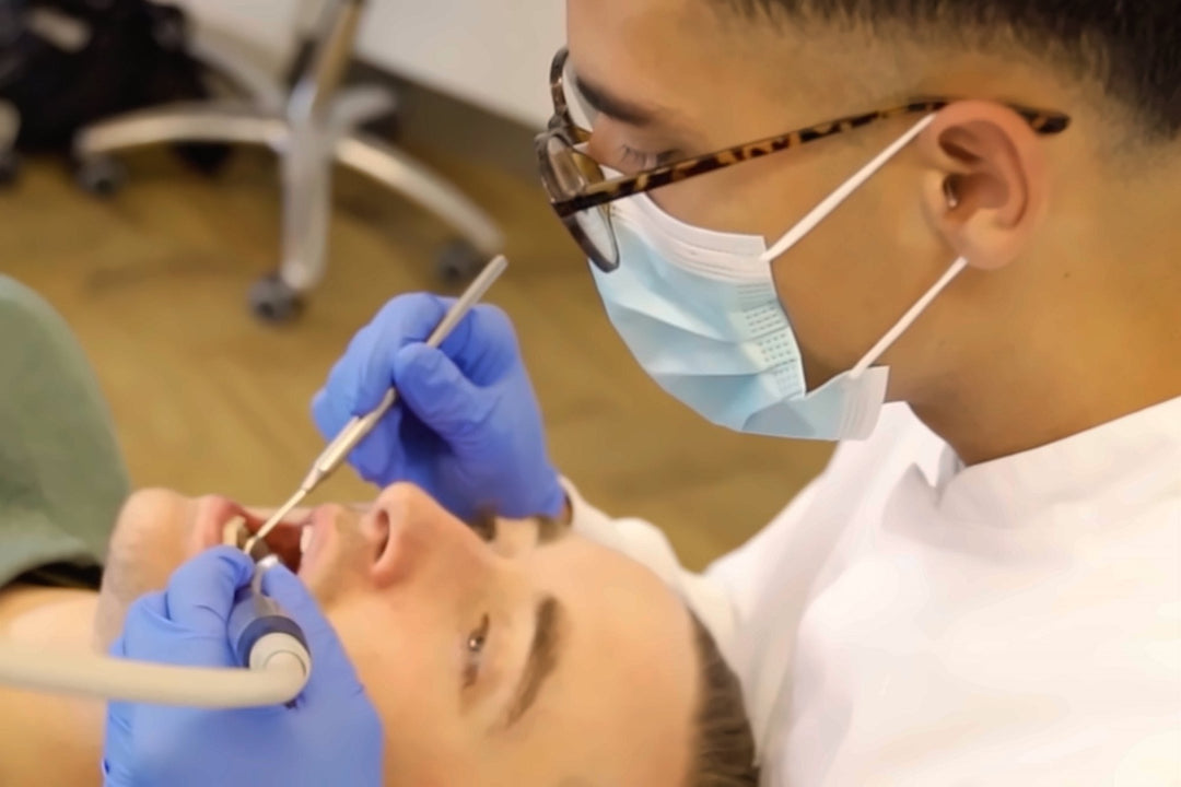 A dental hygienist working chairside with a patient while wearing Earasers